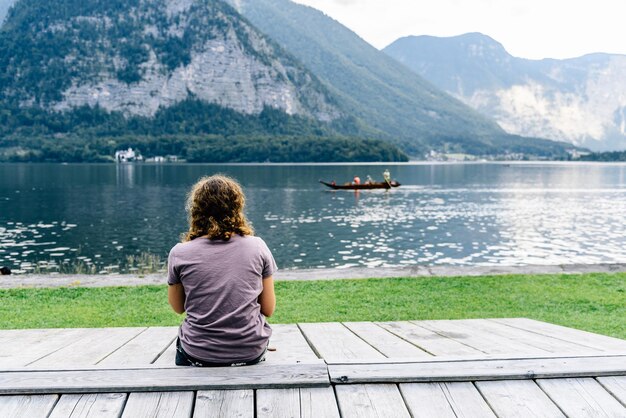 Foto vista posteriore di un uomo seduto su una panchina di legno vicino al lago