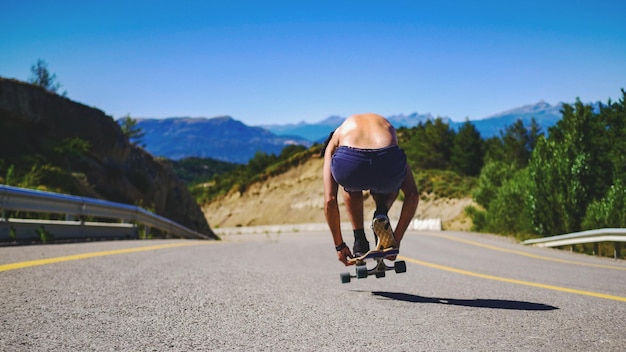 Rear view of man skateboarding on road against sky
