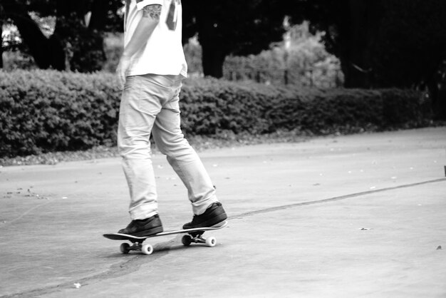 Photo rear view of man skateboarding on road