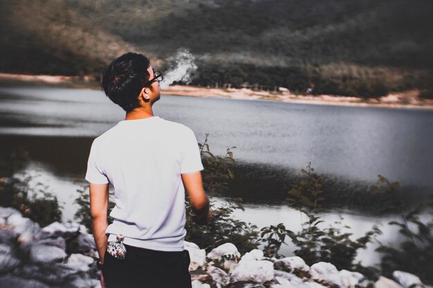 Foto vista posteriore di un uomo che fuma al lago