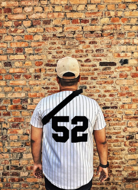 Photo rear view of man standing against brick wall