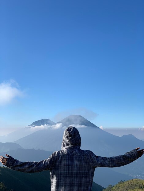 Rear view of man standing against clear blue sky