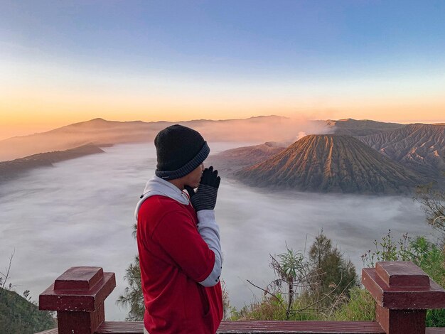 Photo rear view of man standing against mountain during sunset