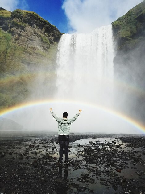 Foto vista posteriore di un uomo in piedi contro la cascata