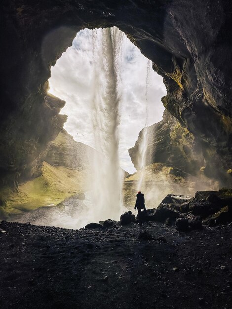 Foto vista posteriore di un uomo in piedi contro la cascata