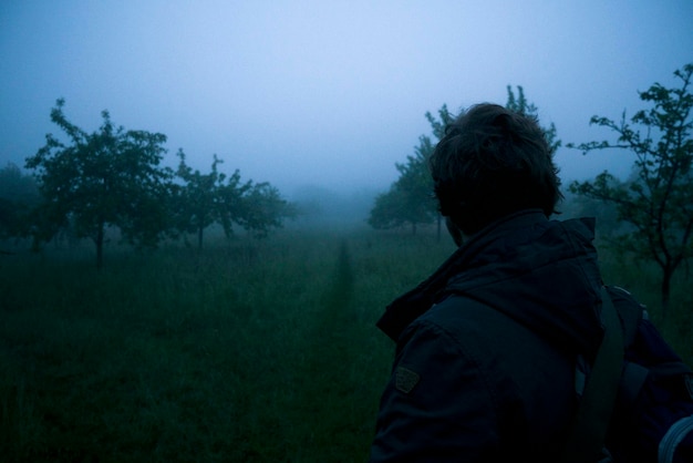 Foto vista posteriore di un uomo in piedi in mezzo alla nebbia sulla terraferma