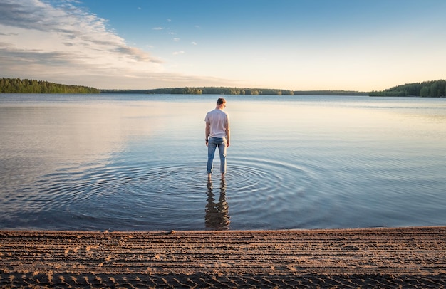 Photo rear view of man standing at beach against sky during sunset