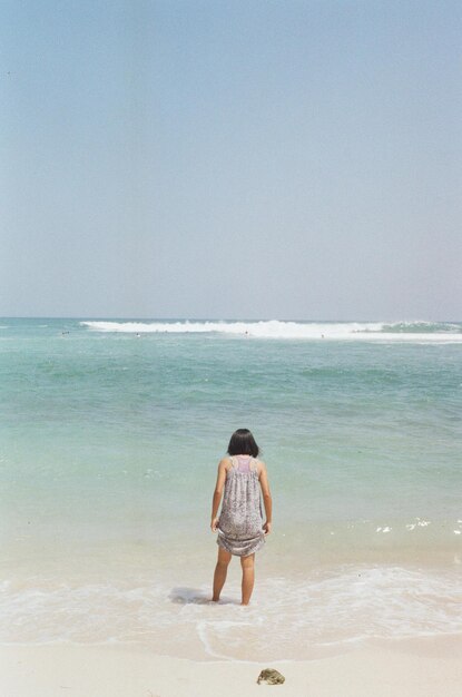 Rear view of man standing on beach against sky