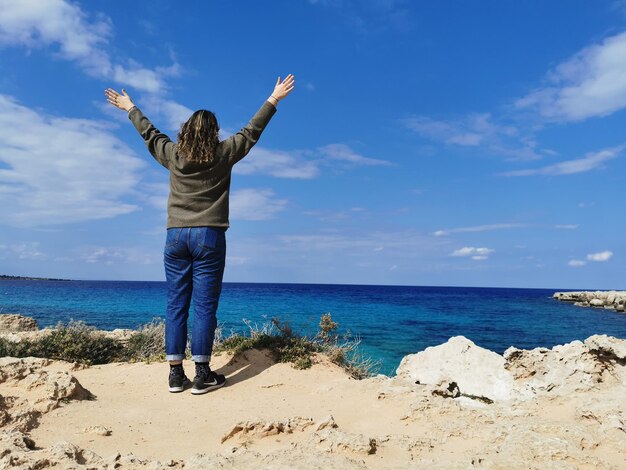 Rear view of man standing at beach against sky