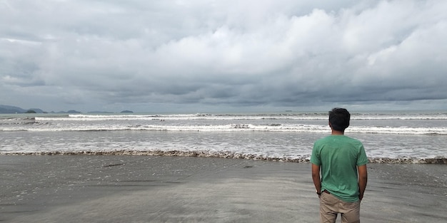 Foto vista posteriore di un uomo in piedi sulla spiaggia