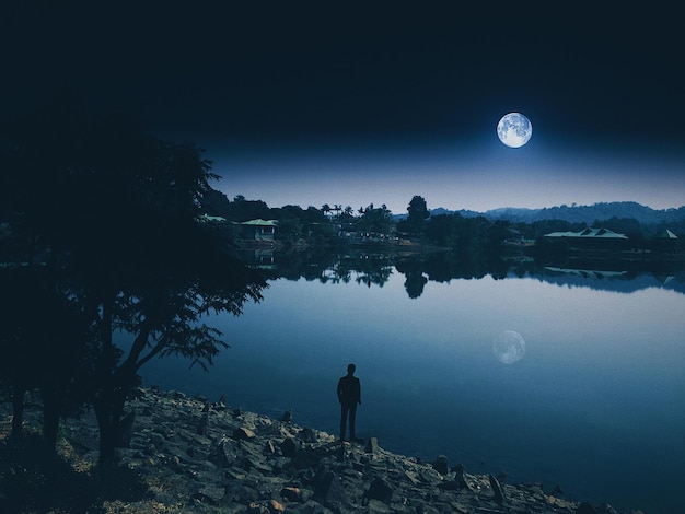 Photo rear view of man standing by lake against sky