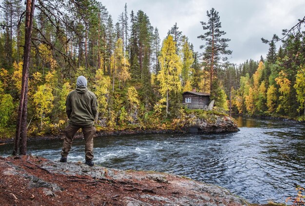 Rear view of man standing by lake in forest