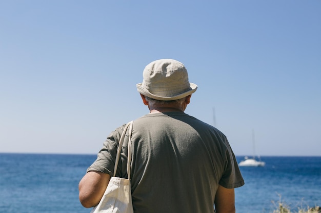 澄んだ空に沿って海に立っている男の後ろの景色