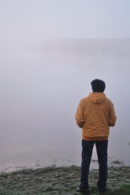 Photo rear view of man standing by sea against sky