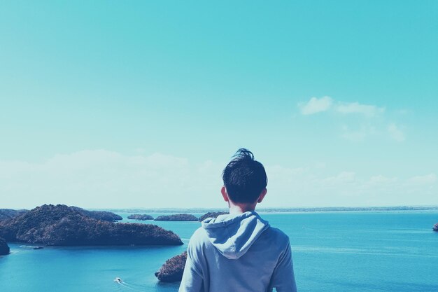 空に照らして海に立っている男の後ろの景色