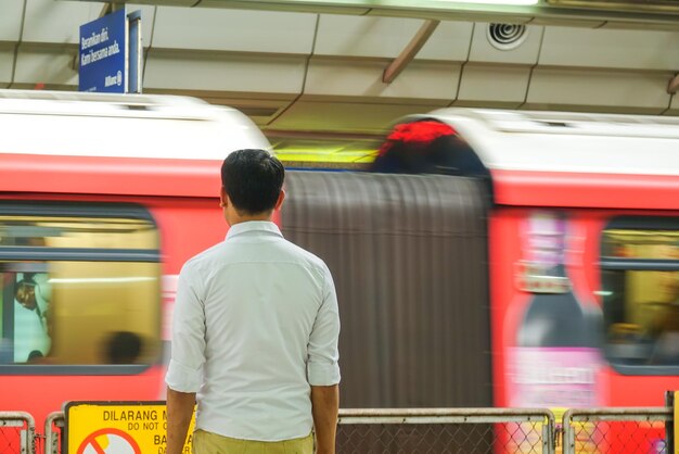 Rear view of man standing by train at railroad station