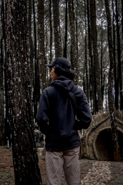 Foto vista posteriore di un uomo in piedi vicino agli alberi nella foresta