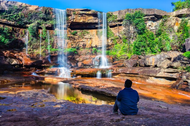 Rear view of man standing by waterfall