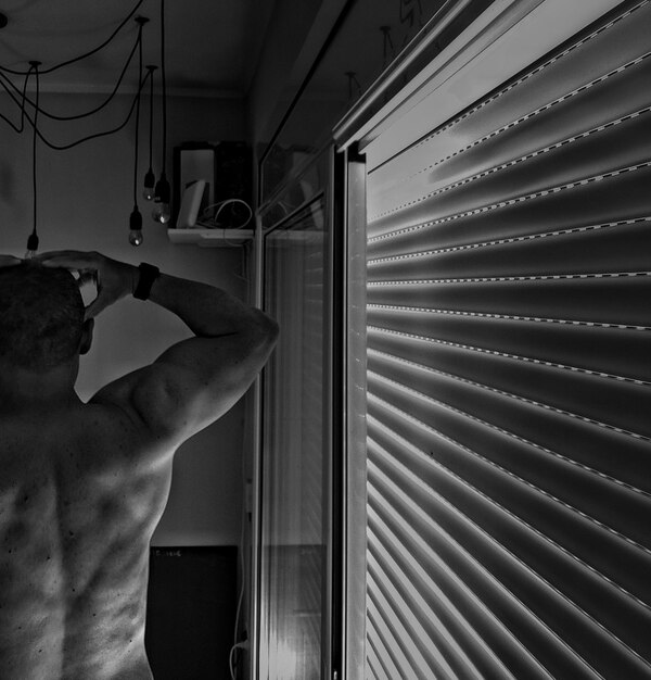 Rear view of man standing by window at home