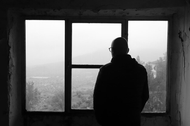 Foto vista posteriore di un uomo in piedi vicino alla finestra