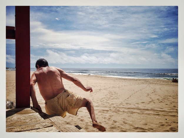 Rear view of man standing on calm beach