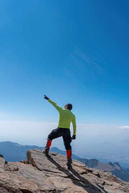 Rear view of man standing at cliff against sky