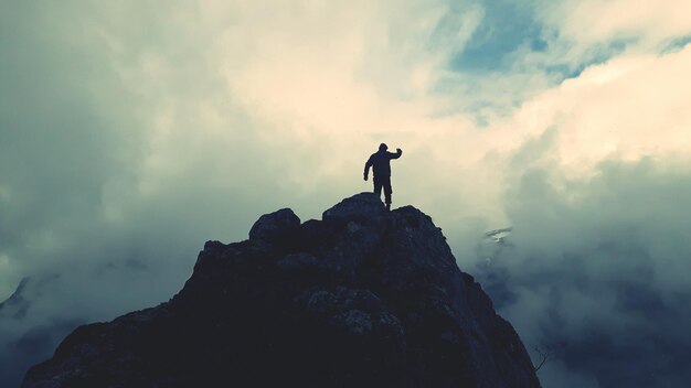 Foto vista posteriore di un uomo in piedi sul bordo di una scogliera contro un cielo nuvoloso