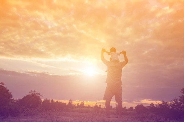 Rear view of man standing on field against sky during sunset