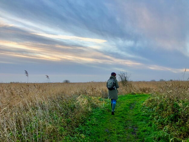 Rear view of man standing on field against sky