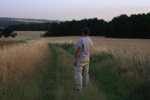 Rear view of man standing on field against sky