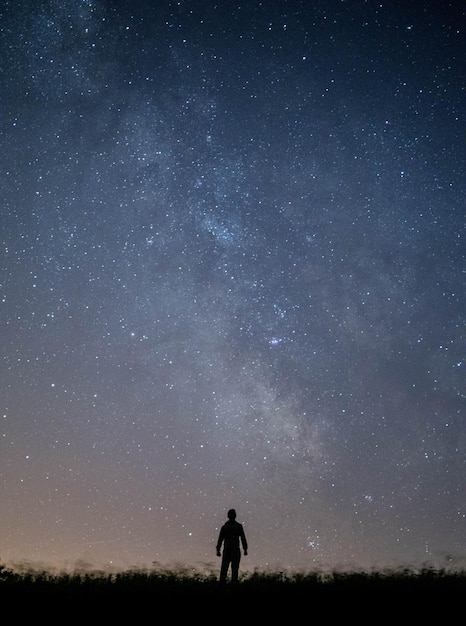 Rear view of man standing on field at night