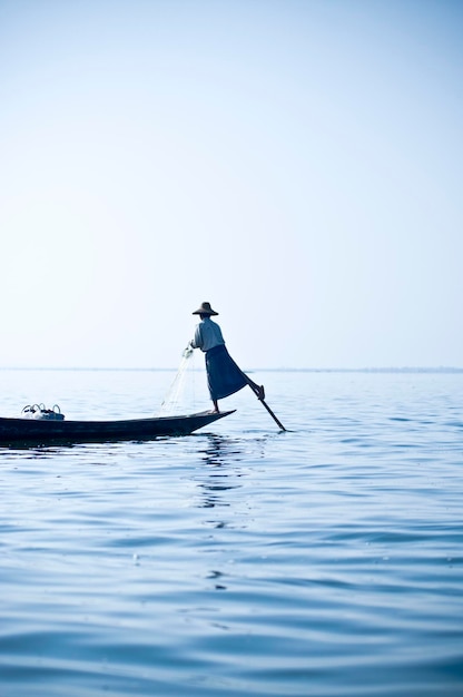 rear view of man standing in fishing boat