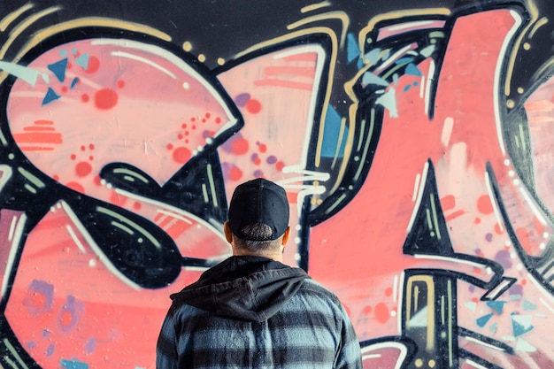 Vista posteriore di un uomo in piedi davanti a graffiti