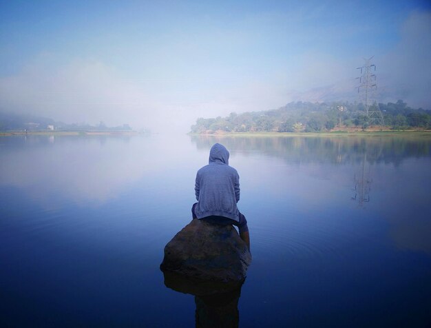 Photo rear view of man standing on lake against sky