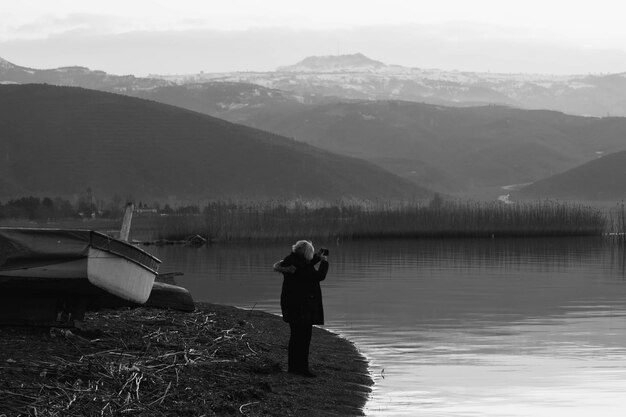 Photo rear view of man standing on lakeshore