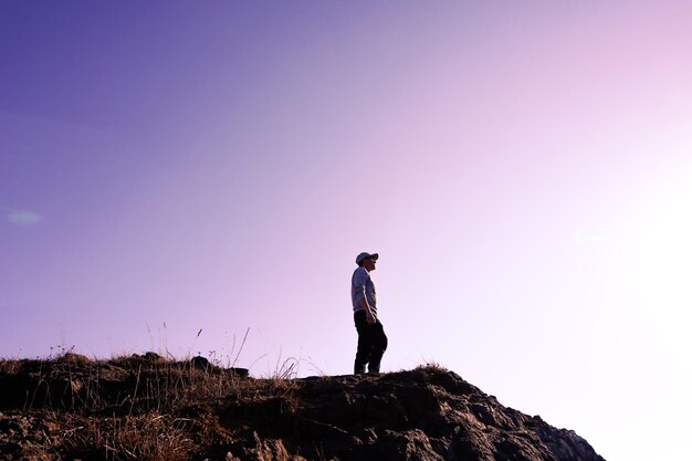 空に照らされた山の上に立っている男の後ろの景色