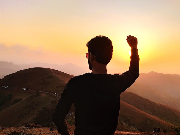 Foto vista posteriore di un uomo in piedi sulla montagna al tramonto