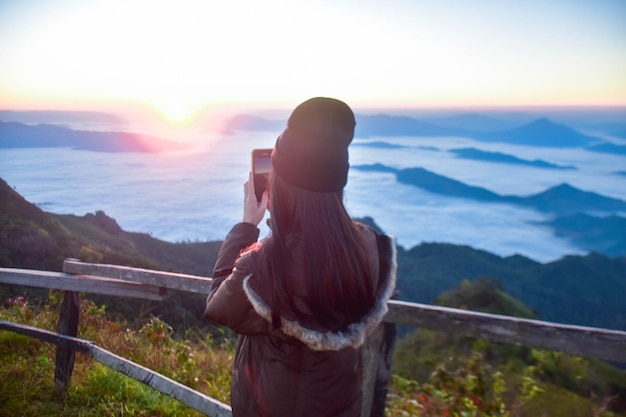 rear view of man standing on railing against mountain