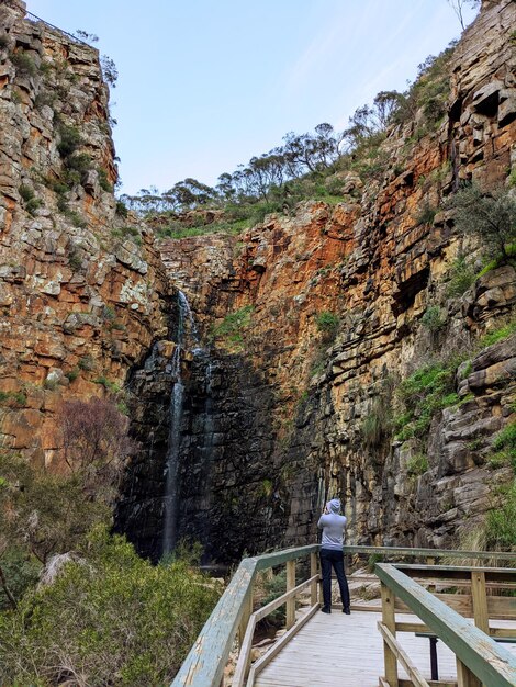 Photo rear view of man standing on railing by mountain