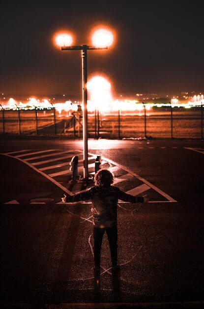 Foto vista posteriore di un uomo in piedi sulla strada di notte