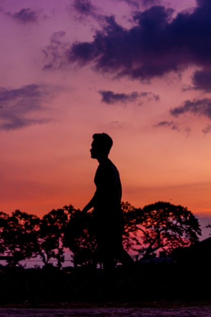 Foto vista posteriore di un uomo in piedi su una roccia contro il cielo durante il tramonto