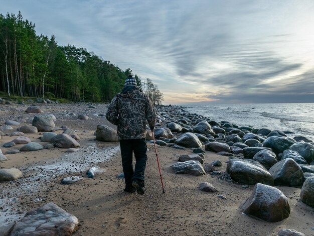 Photo rear view of man standing on rock at beach against sky