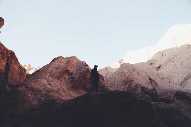 Rear view of man standing on rock formations against sky