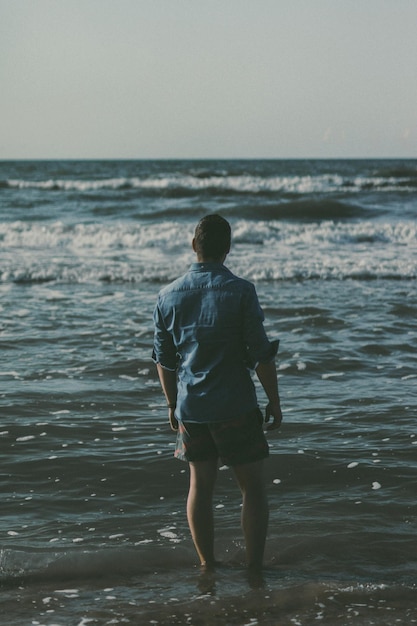 rear view of man standing on shore at beach