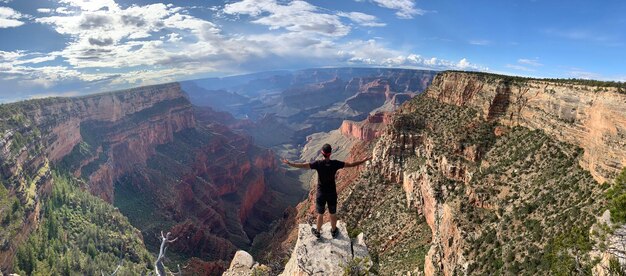 Foto vista posteriore di un uomo in piedi con le braccia stese sulla montagna