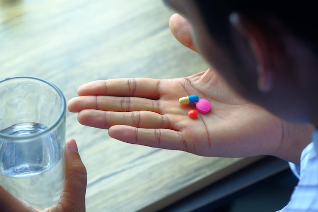 Photo rear view of man taking pills on table