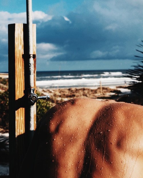 Photo rear view of man taking shower at beach