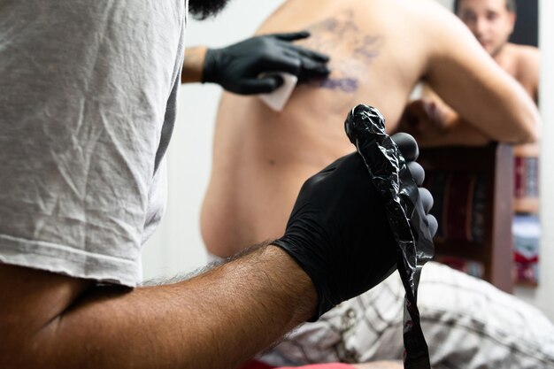 Rear view of man tattooing on customer back