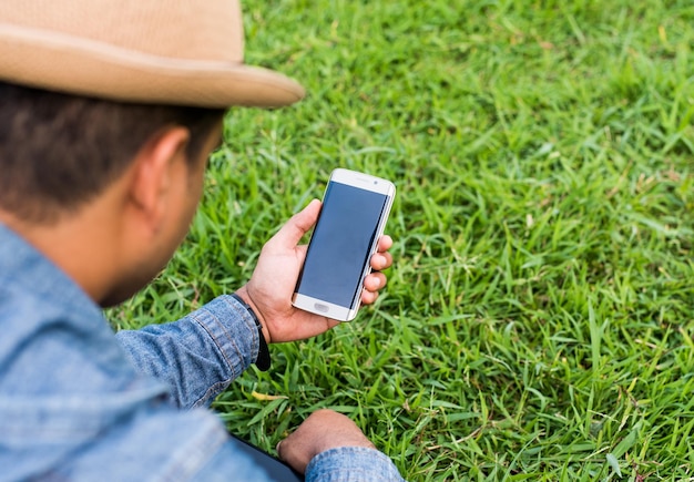 rear view of man using mobile phone on grass