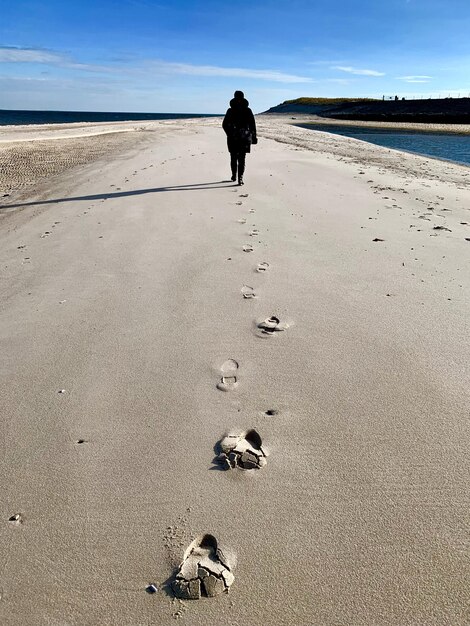 Foto vista posteriore di un uomo che cammina sulla spiaggia